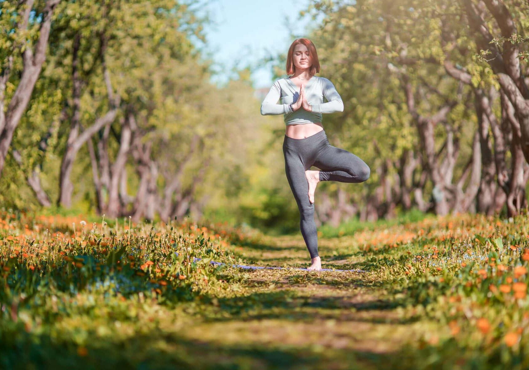 Photo of woman standing on one leg in yoga in forest in afternoon